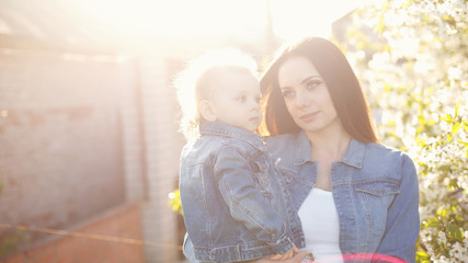 Mother and daughter on a background of a blossoming tree. Girls happy. Spring mood. Family time. Shooting Using the Backlight. Sunset