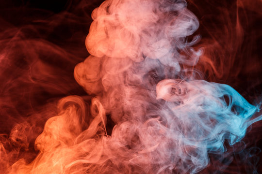 Abstract smoke Weipa. Personal vaporizers fragrant steam. Concept of alternative non-nicotine smoking. Turquoise orange smoke on a black background. E-cigarette. Evaporator. Taking Close-up. Vaping.