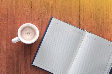 Note book with a cup of coffee on wood table