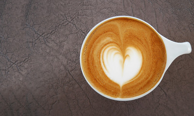 Top view of hot coffee latte art heart shape foam on leather background