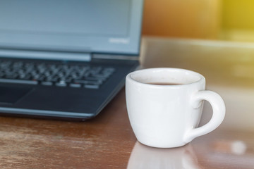 A cup of hot coffee late art in coffee shop with notebook and light