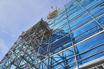 Scaffolding surrounding a tall tower on a sunny day