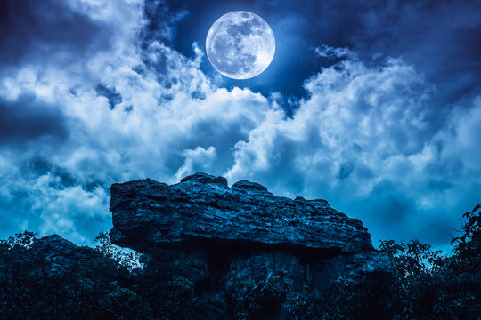 Boulder Against Blue Sky With Clouds And Beautiful Full Moon At Night. Outdoors.