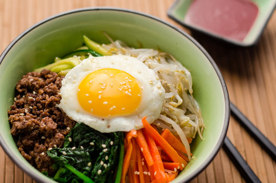 Bibimbap is a classic Korean meal. A bowl of rice is topped with seasoned vegetables, meat and a sunny side up fried egg on top. Spicy chili sauce can be added to finish off this savoury Asian dish.