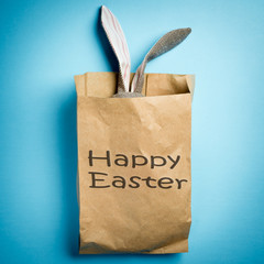 Fototapeta na wymiar Easter bunny in a paper bag. Rabbit. Blue background. Easter ideas. Easter eggs. Space for text. Black lettering happy easter.
