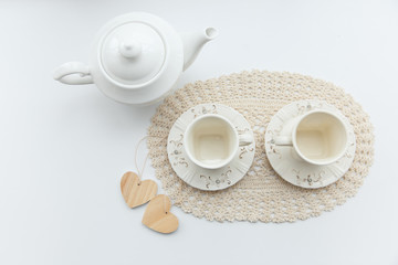 Tea for two. Two white cups of tea with two hearts and kettle.