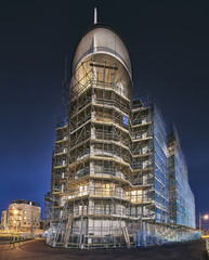 Fototapeta na wymiar Scaffolding around a tall modern building under construction