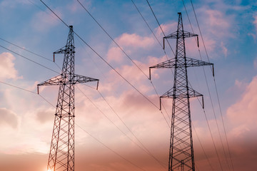 Silhouette of high voltage electrical pole. Sunset sky background.