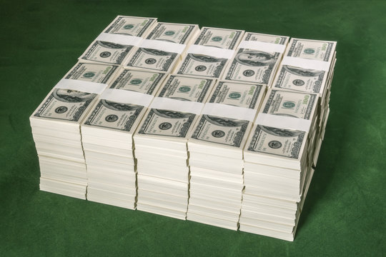 Stacks of one million US dollars in hundred dollar banknotes on green table