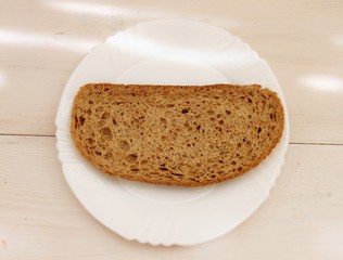 Slice of dark bread with bran on the white plate