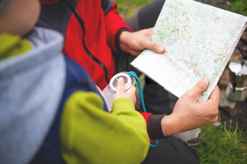 The boy with his father holding a compass and a map.