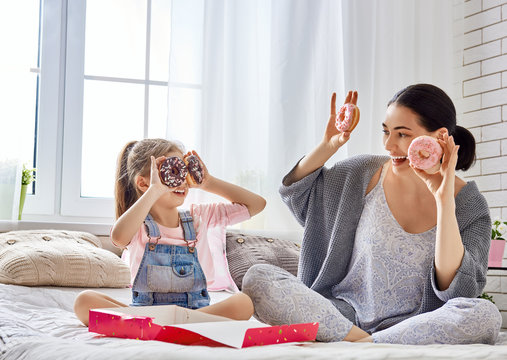 Mother And Her Daughter Eating Donuts