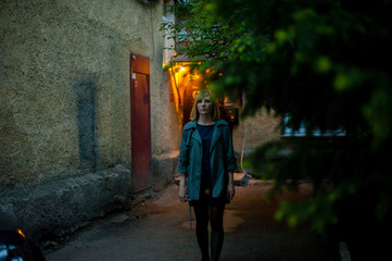 Obraz premium outdoor portrait of young blonde woman, wearing a raincoat, smoking electronic cigarette