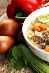 Clear soup with beef and noodles. Broth with carrots, onions var
