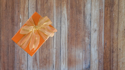 Golden gift box with a ribbon on a wooden floor.