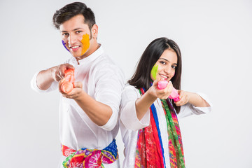 Indian Couple showing their colored hands or with pichkari or sweet laddu on Holi festival,...