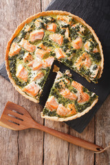 Savory food: sliced tart with salmon, spinach and cream close-up. vertical top view