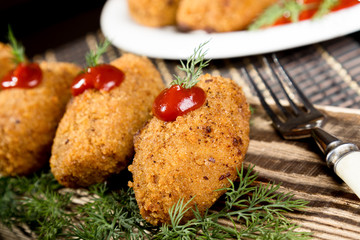 Homemade meat cutlets with parsley and ketchup on wooden plate