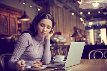 Beautiful brunette using laptop in cafe. Blogger work concept