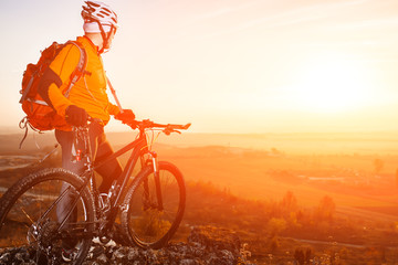 low angle view of cyclist standing with mountain bike on trail at sunset