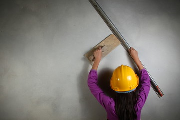 The girl in action of doing plaster work represent the people and construction concept related background.