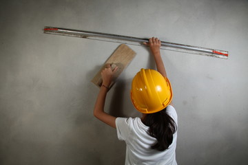 The girl in action of doing plaster work represent the people and construction concept related background.