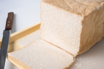 View of a loaf of homemade bread and a slice on a wooden breadboard with a bread knife.