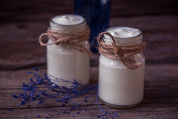 Yogurt in jar on the wooden table with purple dried plant