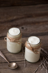 Obraz na płótnie Canvas Yogurt in jars on the wooden table with dried plant