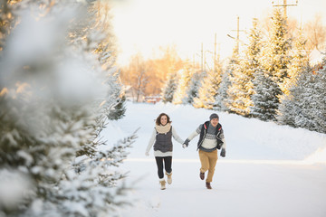 Fototapeta na wymiar happy loving couple walking in snowy winter forest, spending christmas vacation together.