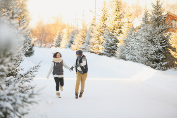 happy loving couple walking in snowy winter forest, spending christmas vacation together.