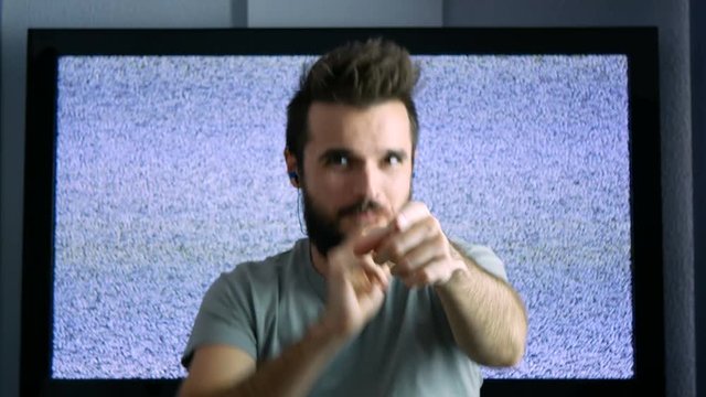 Self-confident bearded man with earphones dancing and listening trap hip-hop music with large grainy screen on the background.