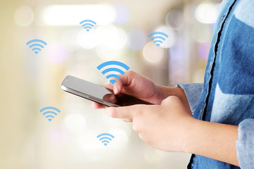 Hand using smart phone and wifi icon over blur background