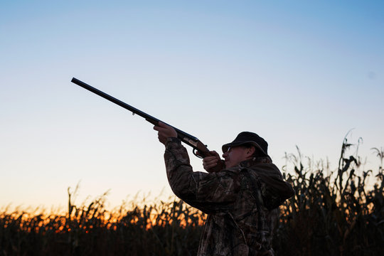 Hunter aiming at ducks at sunset
