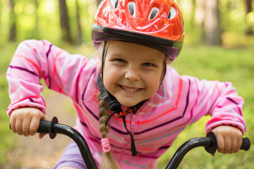 Naklejka premium Little girl riding a bicycle in the woods