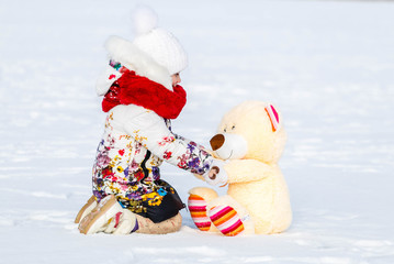 Little girl with her toy playing on the snow
