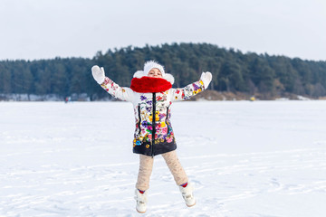 Little girl in warm clothes in winter outdoors
