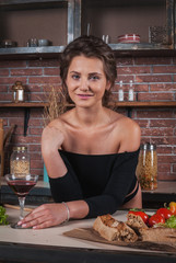 Young woman standing in kitchen holding red wine glass