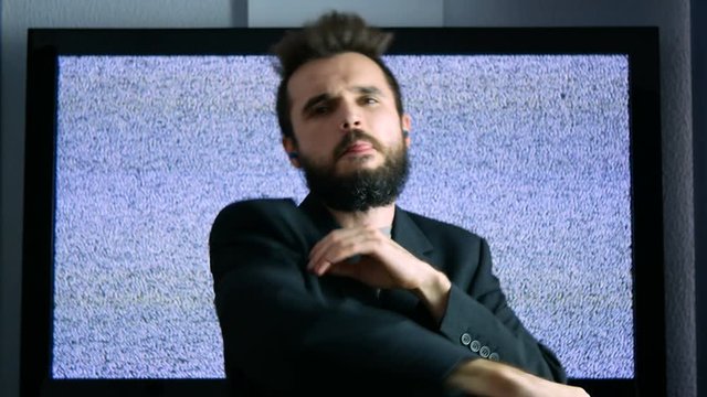 Self-confident bearded businessman dancing on trap hip-hop music and showing illuminati sign with large grainy screen on the background.