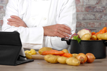 detail of hands of chef using tablet for cooking