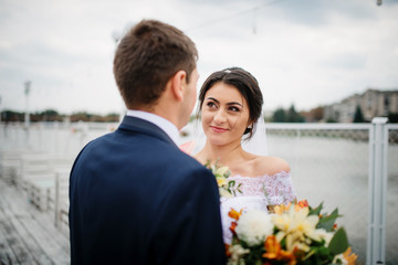Wedding couple stay on the pier berth at cloudy day.