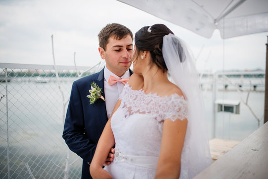 Wedding couple stay on the pier berth at cloudy day.