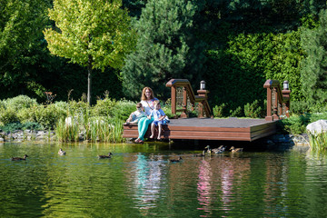 Family happiness Happy mother tenderly embracing his two sons children on grass in spring day, warm feelings of the , lifestyle moment