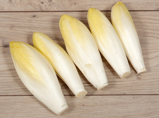 Top view on endives lying on wooden background.