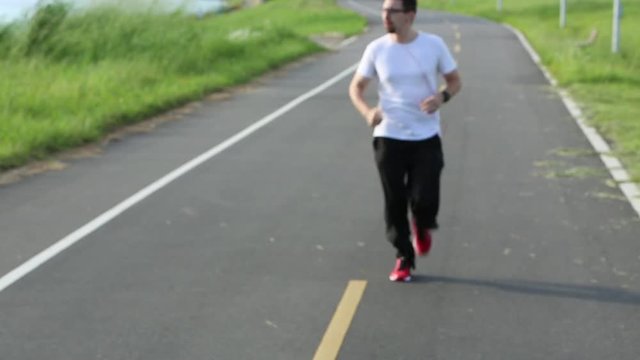 Caucasian man drinking water after jogging in the road of teh park Taiwan. Exercising Concept. Sports lifestyle -Dan