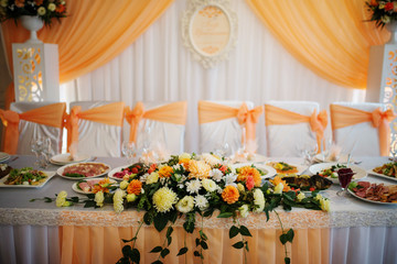 Orange composition of flowers on table of newlyweds.