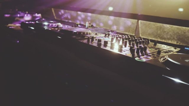 behind dj decks and mixer in night club, dolly slider shot
