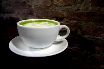 Matcha green tea latte cup on brick wall background