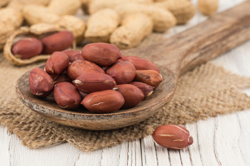 Peanut closeup on a wooden spoon and a wooden table.