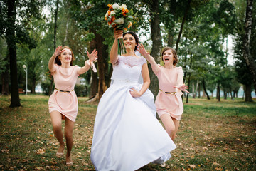 Bride with bridesmaids throw bouquet at wedding day.